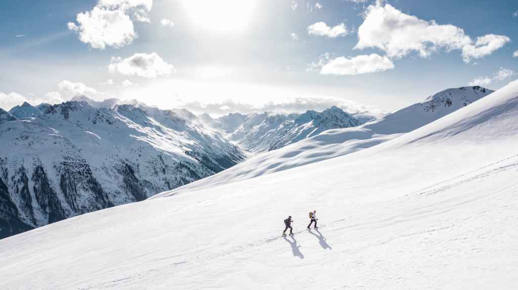 two people climbing up a snowy hill 
